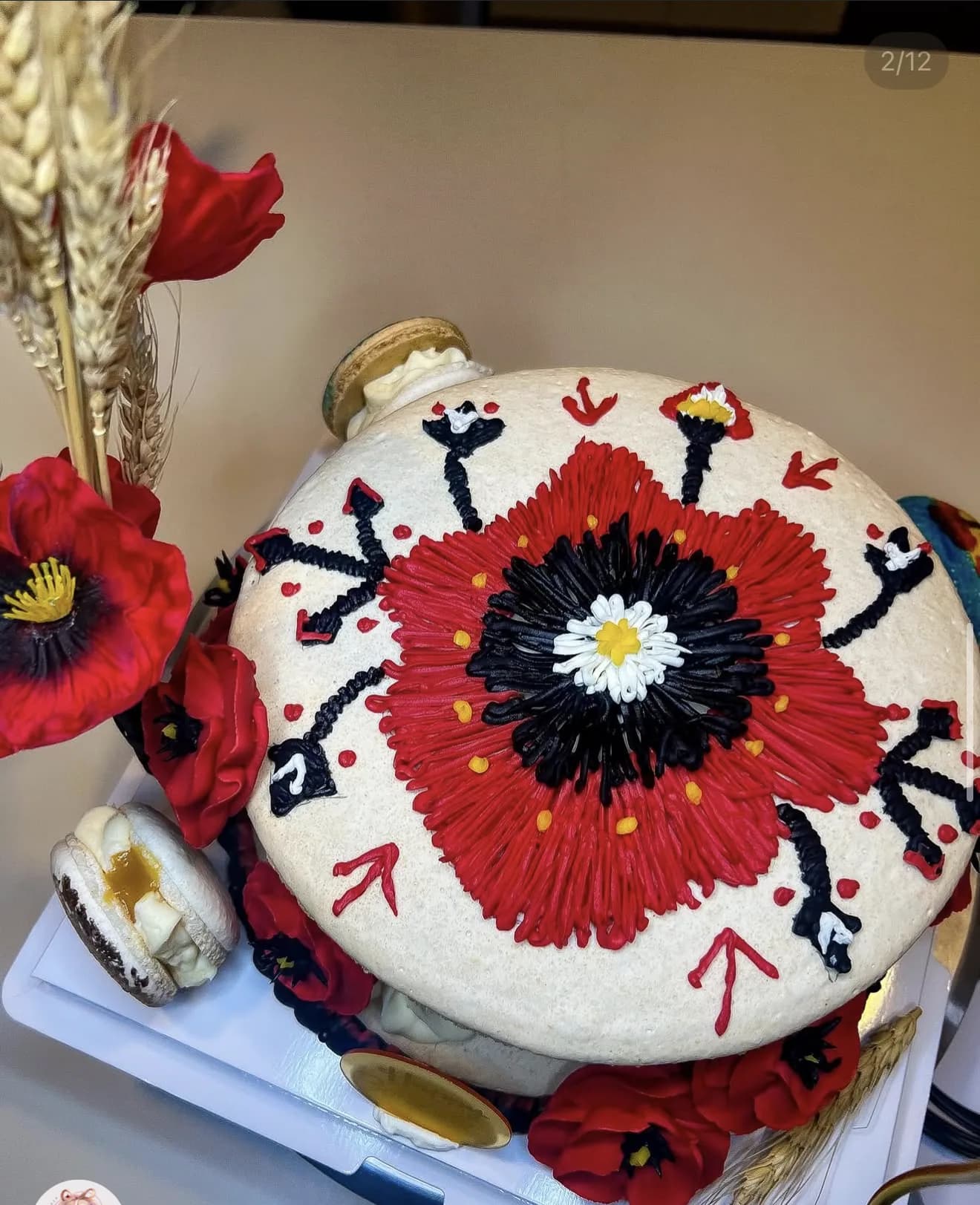 Overhead view of hand-piped red poppy folk art cake surrounded by poppies and wheat
