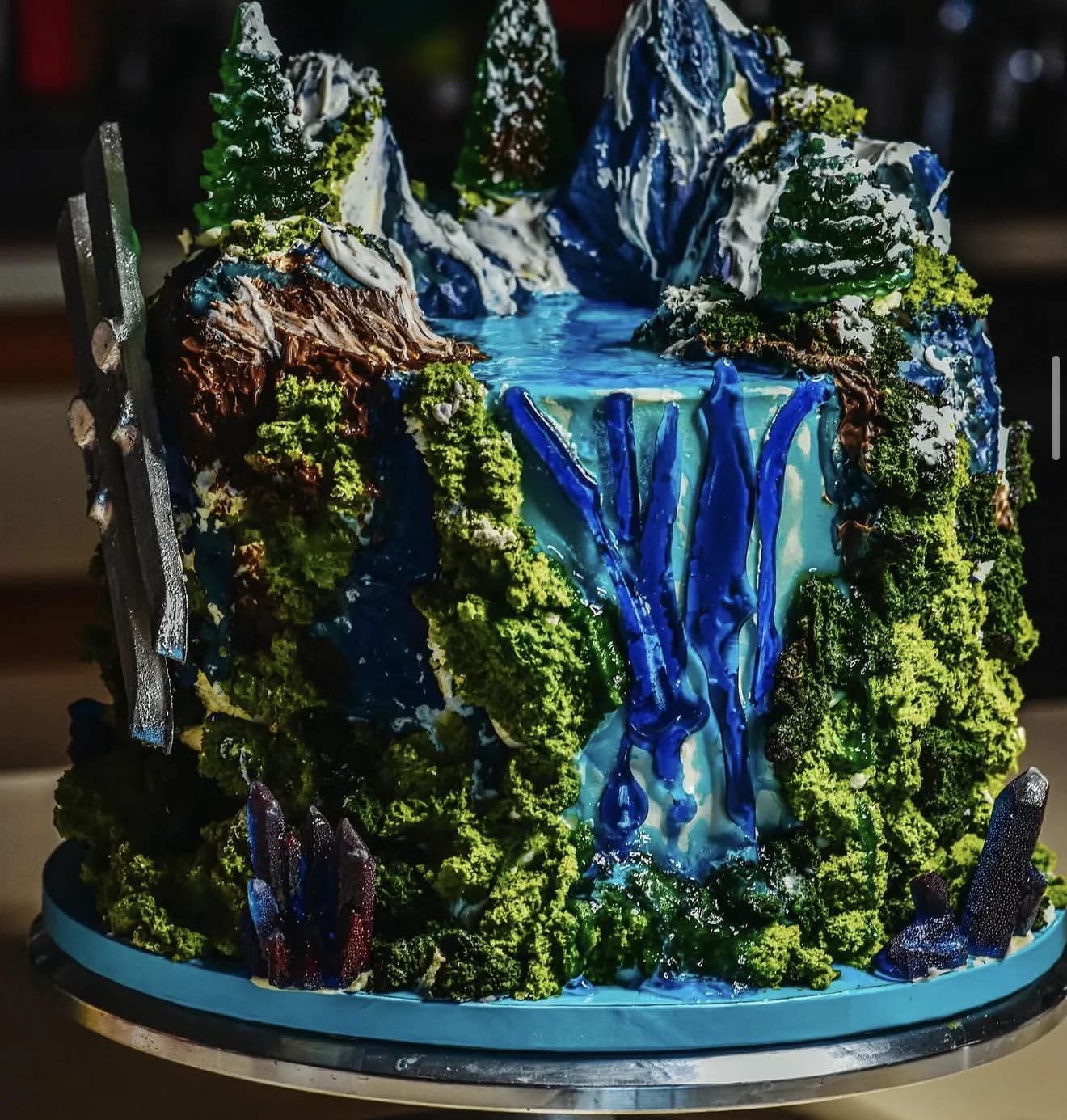 Sculptural mountain and waterfall cake with pine trees, amethyst crystals and moss-like texture