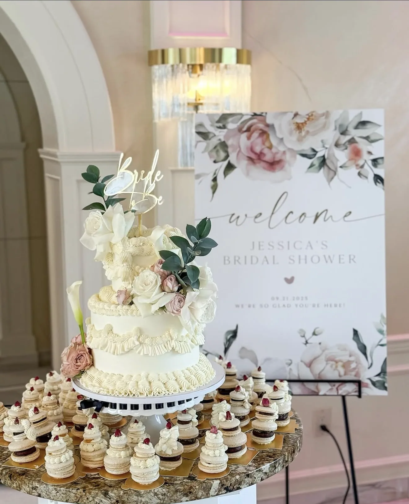 Two-tier white buttercream bridal shower cake with Bride to Be topper and mini cakes around base