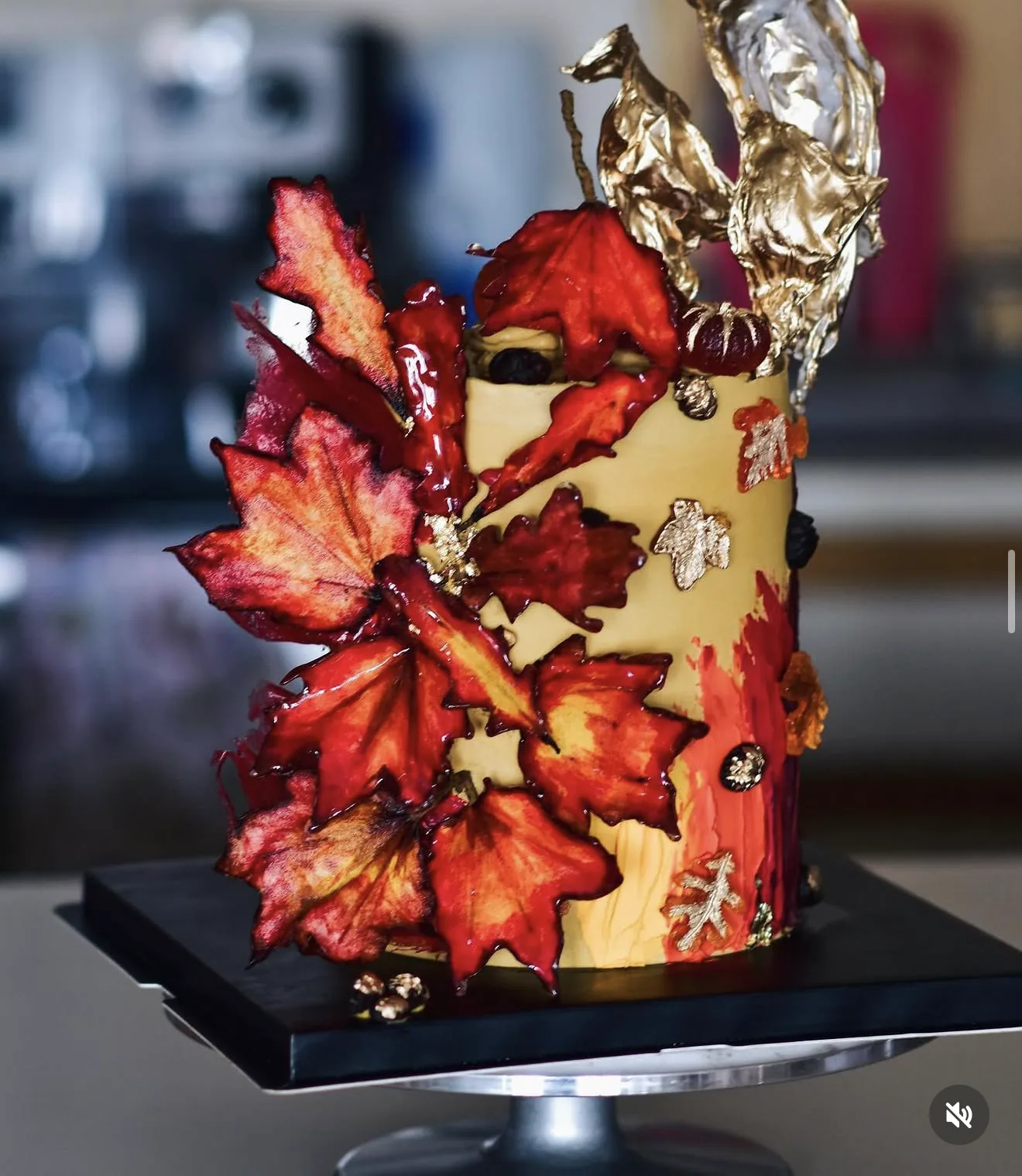 Autumn cake with sculpted red sugar maple leaves cascading upward topped with gold foil