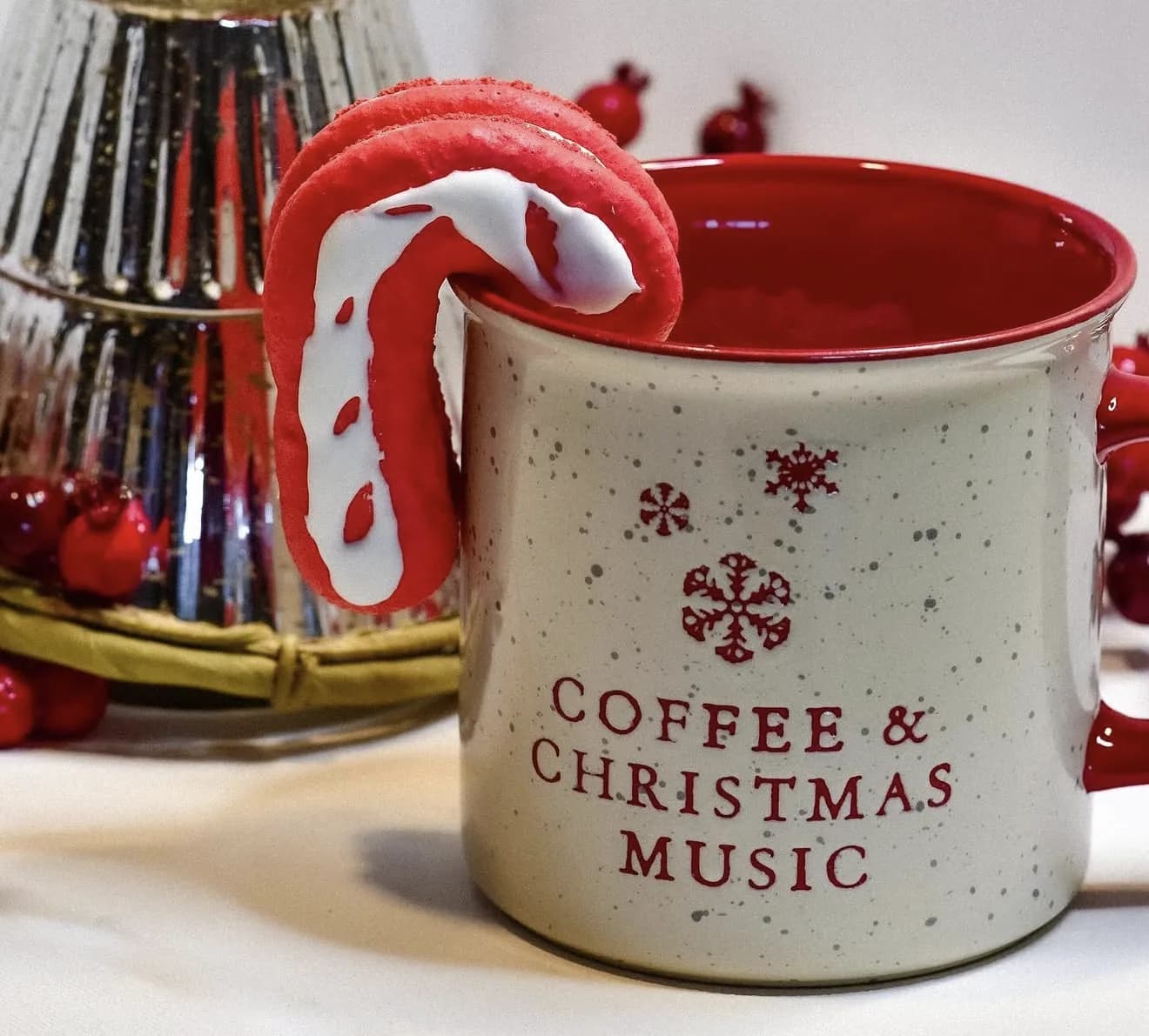 Macaron piped as red and white candy cane perched on a Coffee and Christmas Music mug