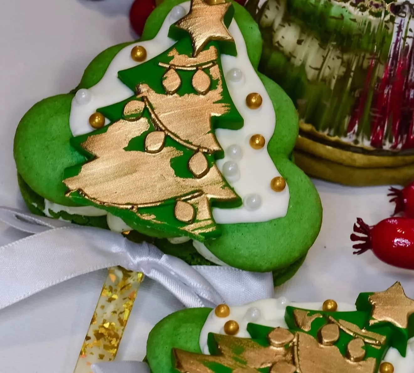 Green Christmas tree shaped macarons with hand-painted gold tree and pearl ornament detail