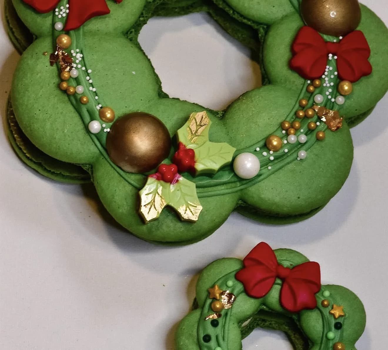 Large green wreath-formed macaron assembly with gold pearls red bow and holly details