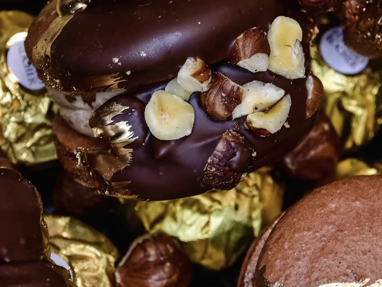Chocolate macarons topped with chopped hazelnuts on bed of foil-wrapped Ferrero Rocher candies