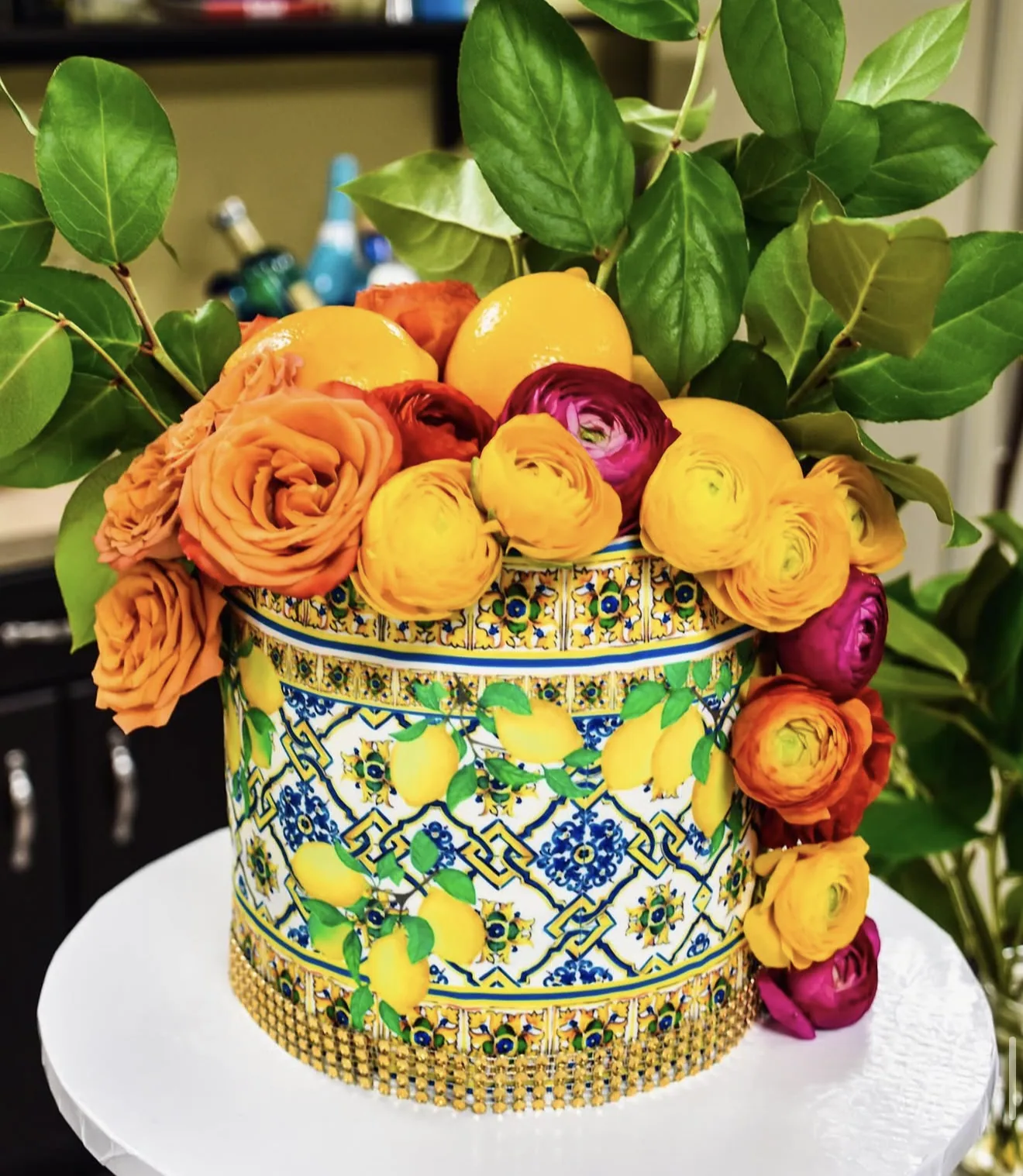 Second angle of Sicilian majolica tile painted cake with lemon and ranunculus bouquet overflow