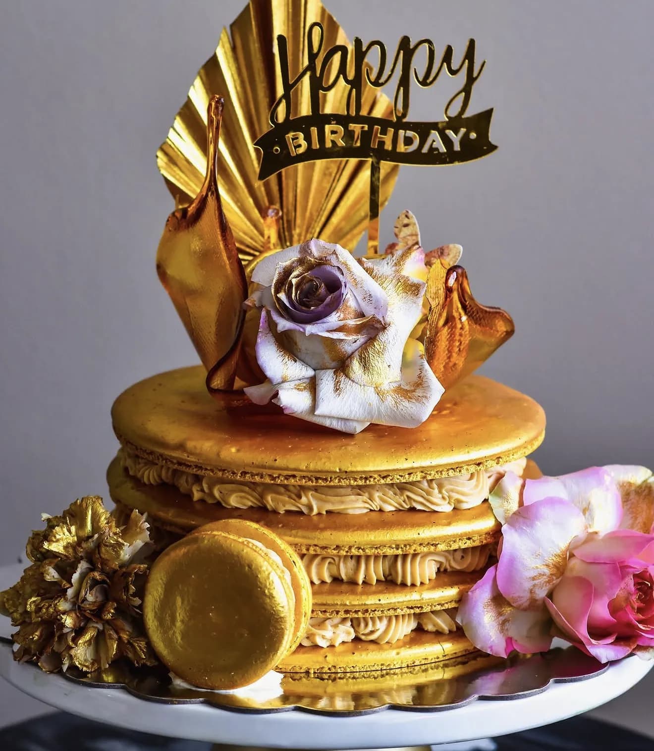 Gold-painted layered macaron cake with sugar rose amber sugar shards and blush flowers
