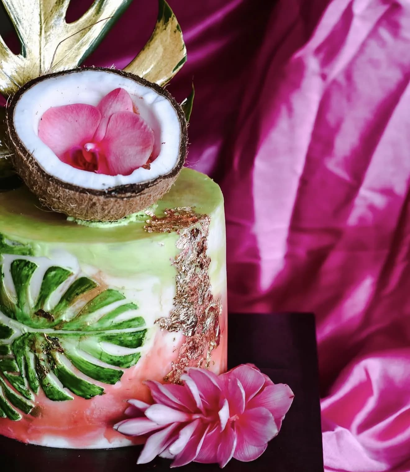 Tropical cake with hand-painted monstera leaves opened coconut and bird of paradise on satin