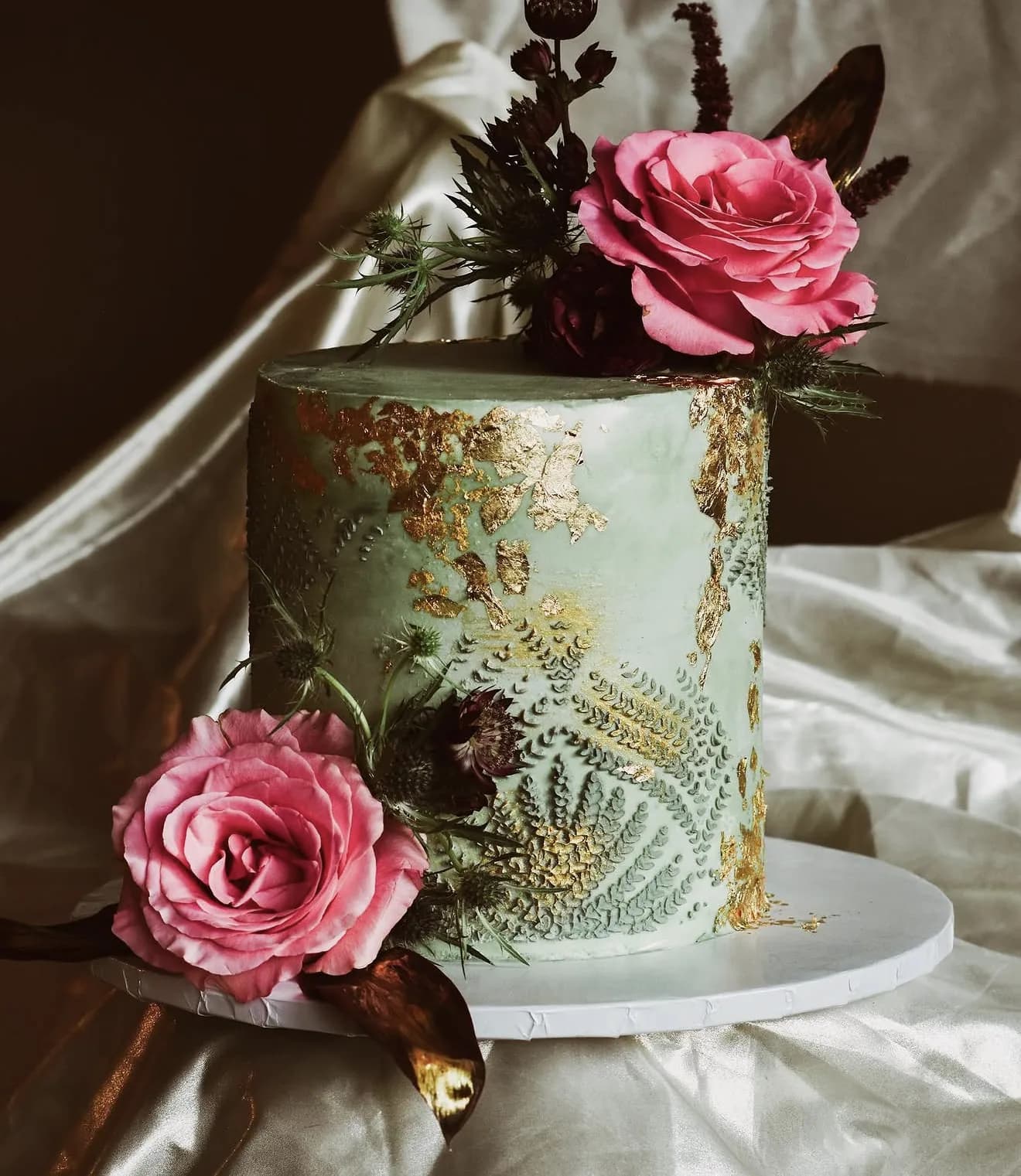 Sage green cake with gold leaf accents piped fern texture and pink peonies thistle roses