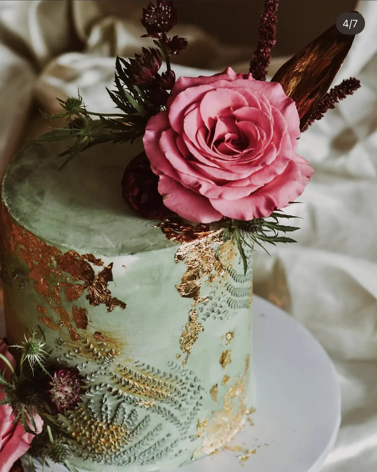 Alternate sage velvet cake view with larger pink rose and piped foliage under gold flecks