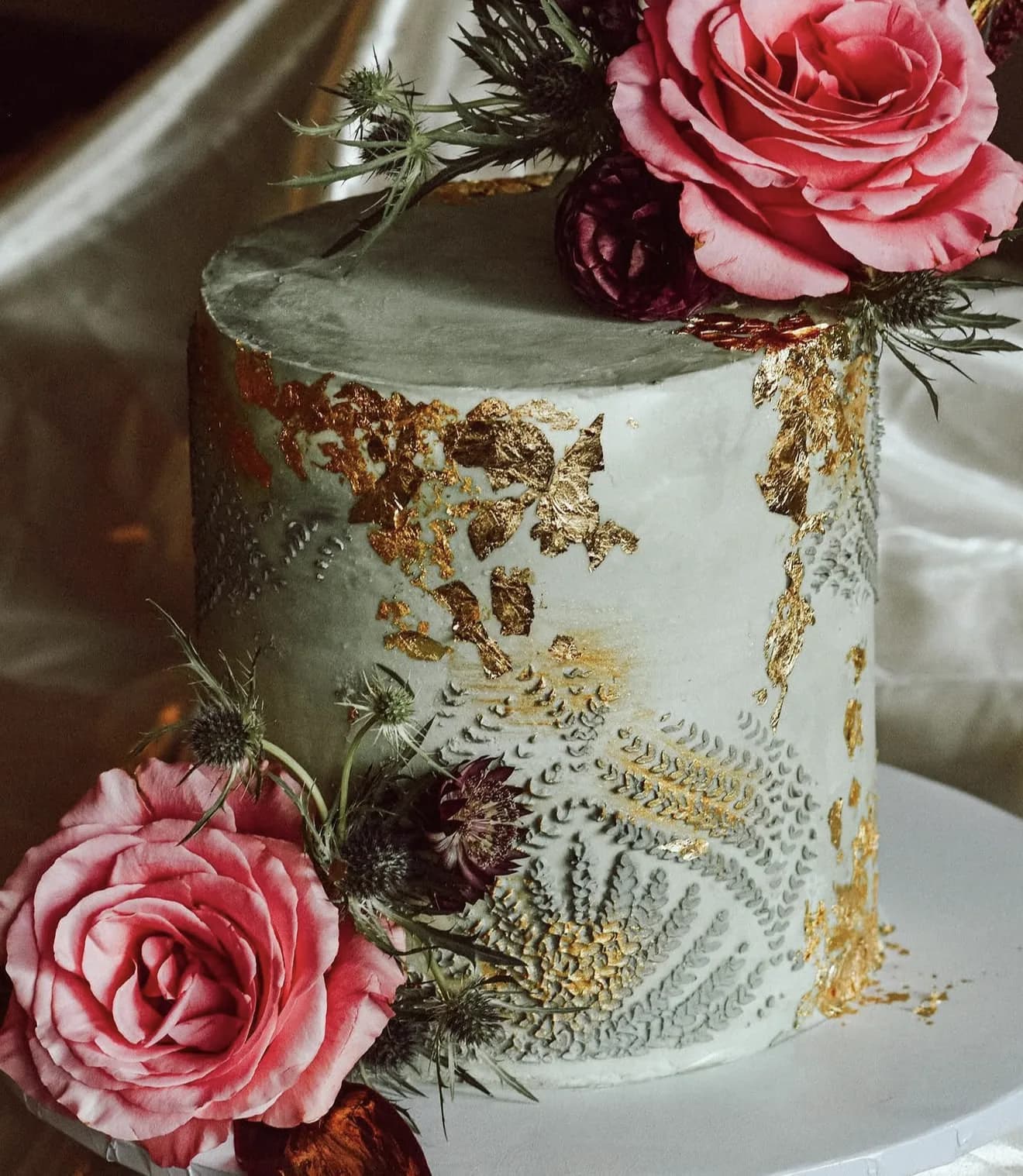 Top-down detail of sage velvet cake showing gold leaf flakes and piped fern texture