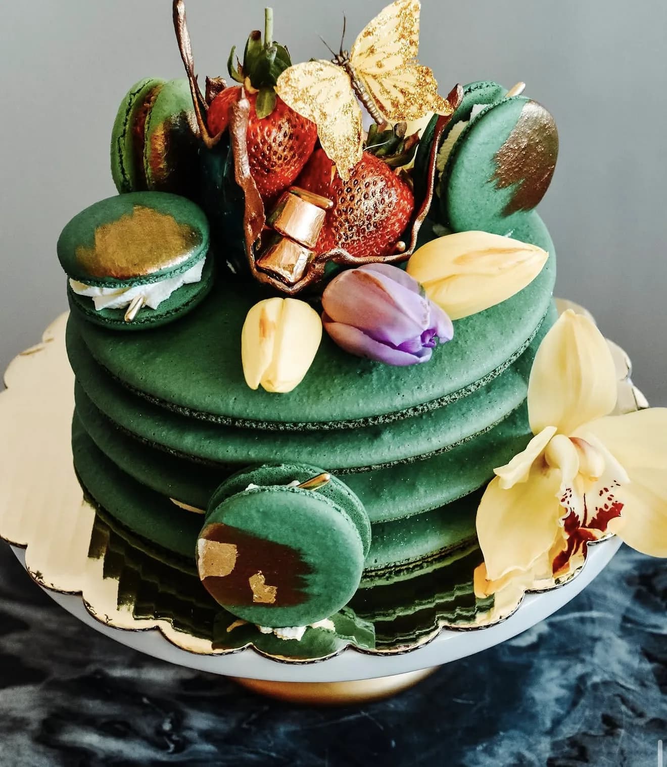 Rotated view of emerald macaron tower with painted gold accents and butterflies