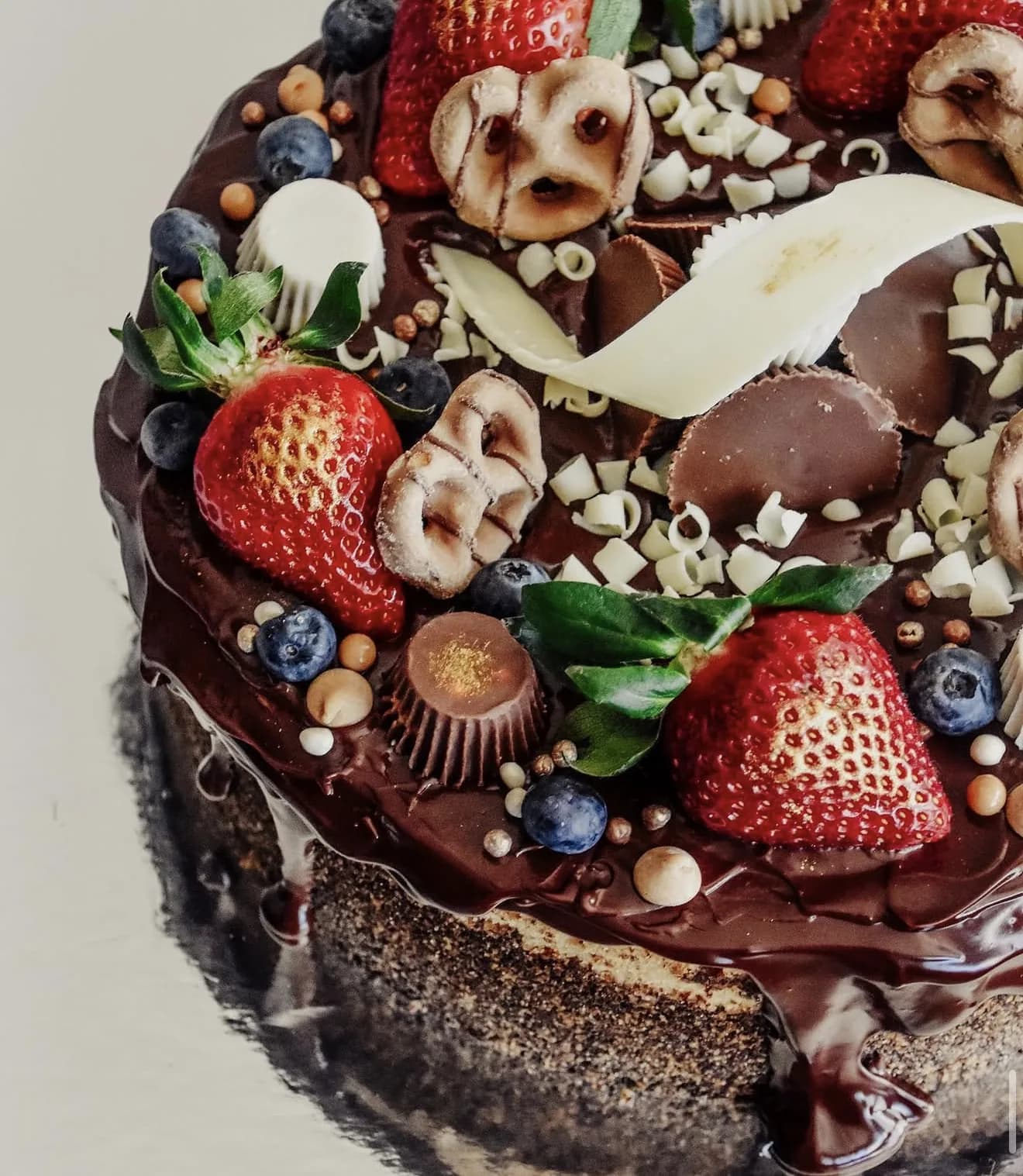Chocolate ganache cake topped with strawberries mini peanut butter cups and white chocolate shavings