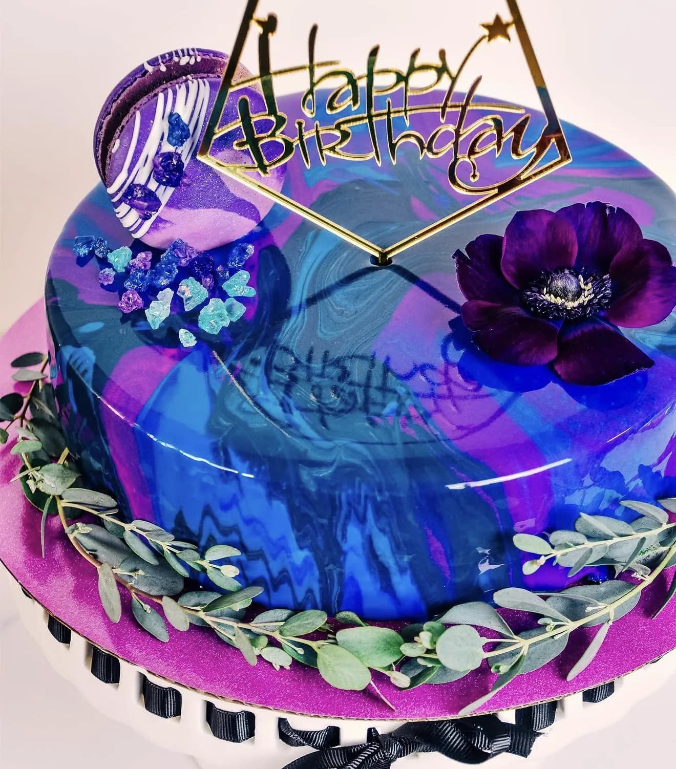 Purple and blue galaxy mirror glaze cake with sugar crystal shards and purple anemone flower