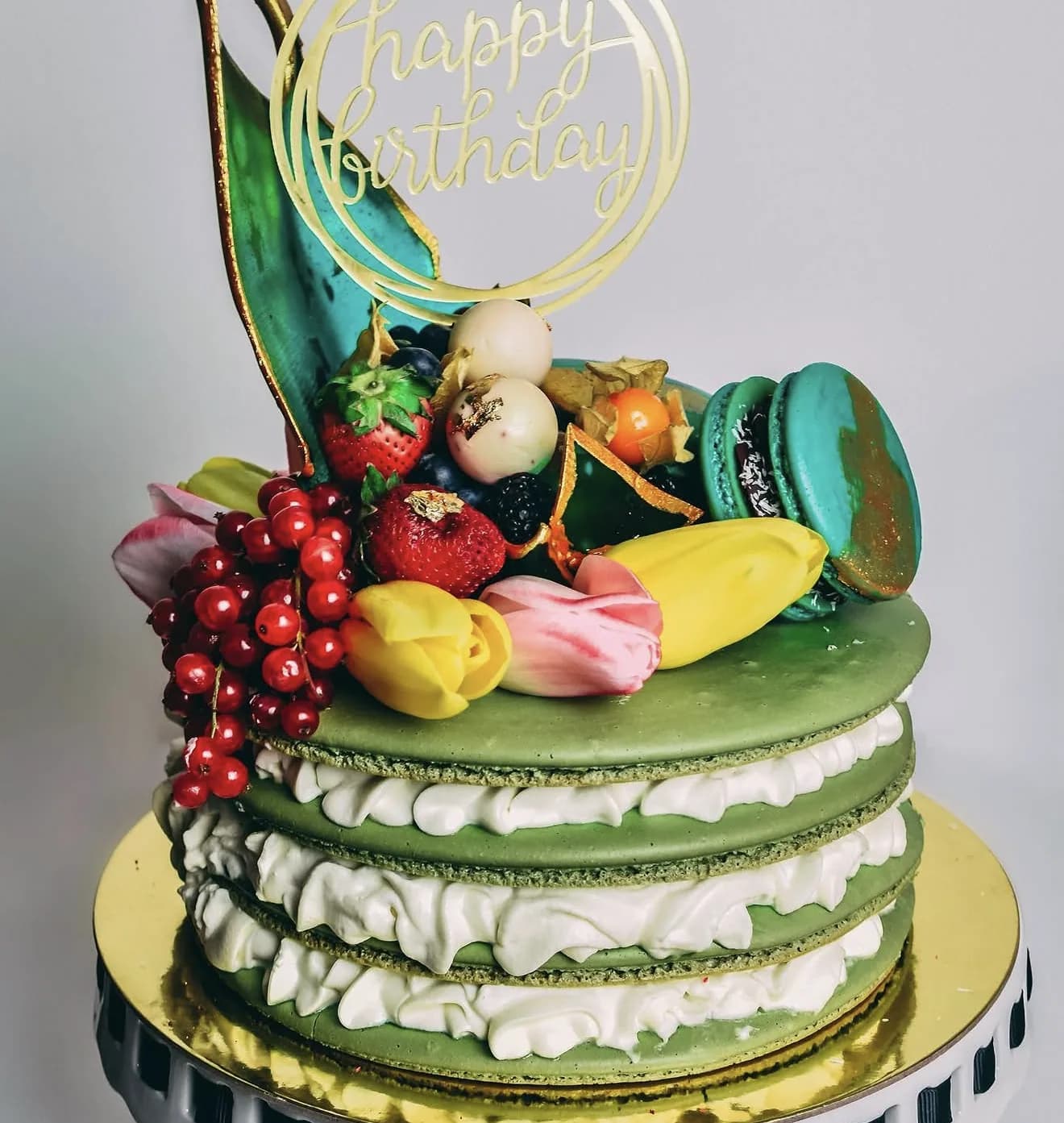 Matcha dusted mega macaron tower topped with banana tulip red currants and teal macaron