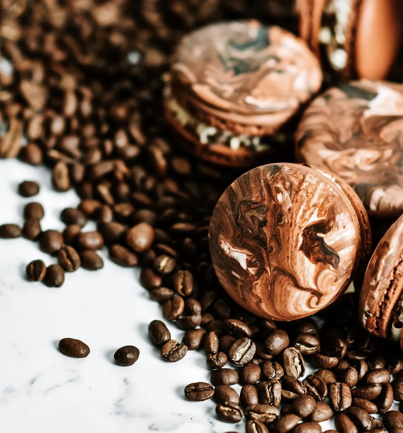Macro shot of marbled mocha macaron on marble surface sprinkled with coffee beans