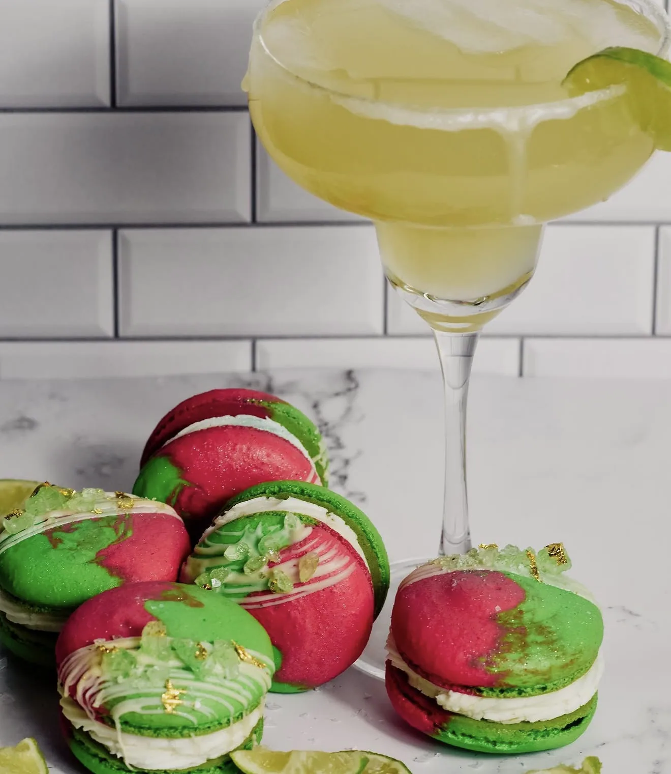 Red and green lime margarita macarons with drip detail beside cocktail glass rimmed with salt