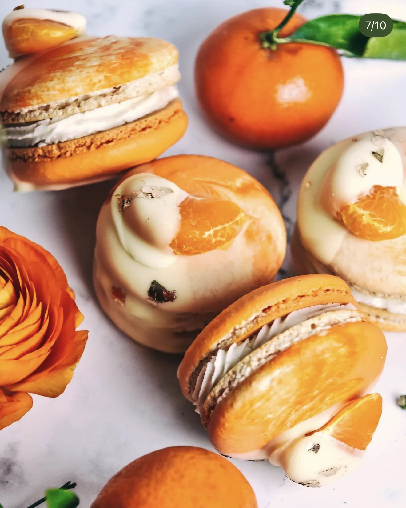 Orange tangerine macarons and white chocolate coated spheres with mandarin slices and ranunculus