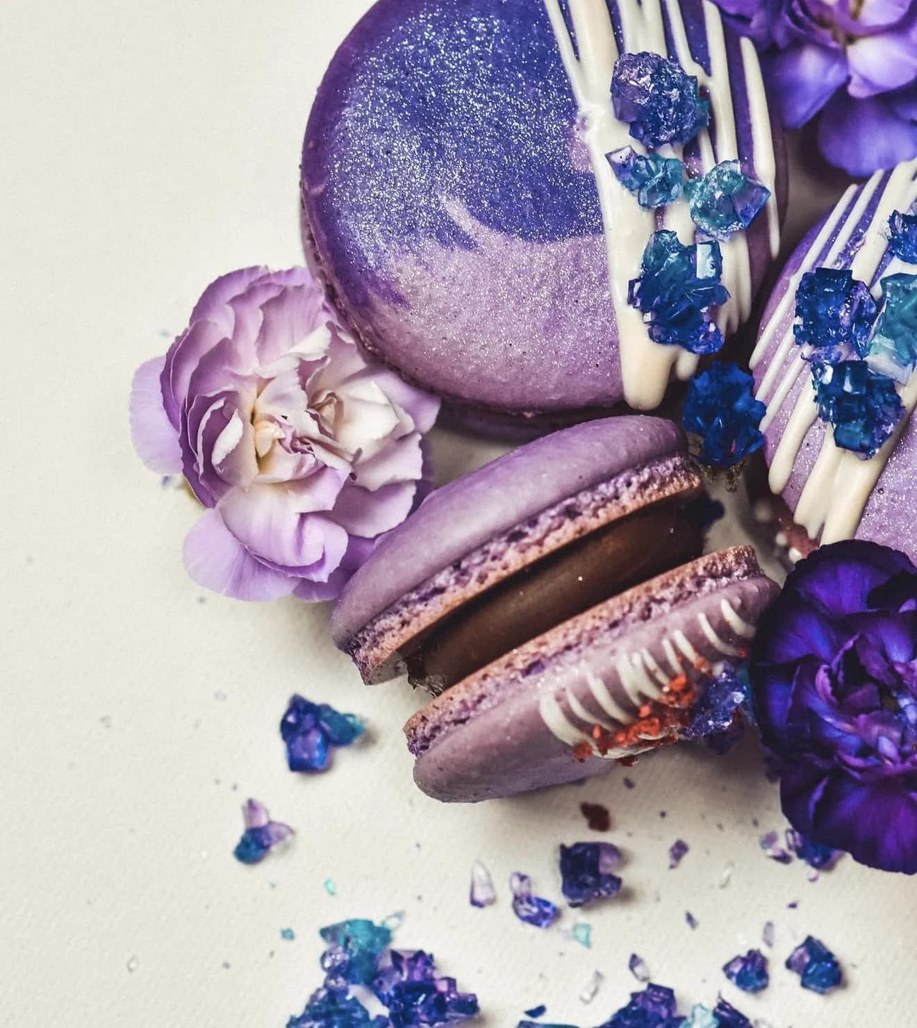 Cluster of purple amethyst macarons with carnations and sugar crystal scatter against white