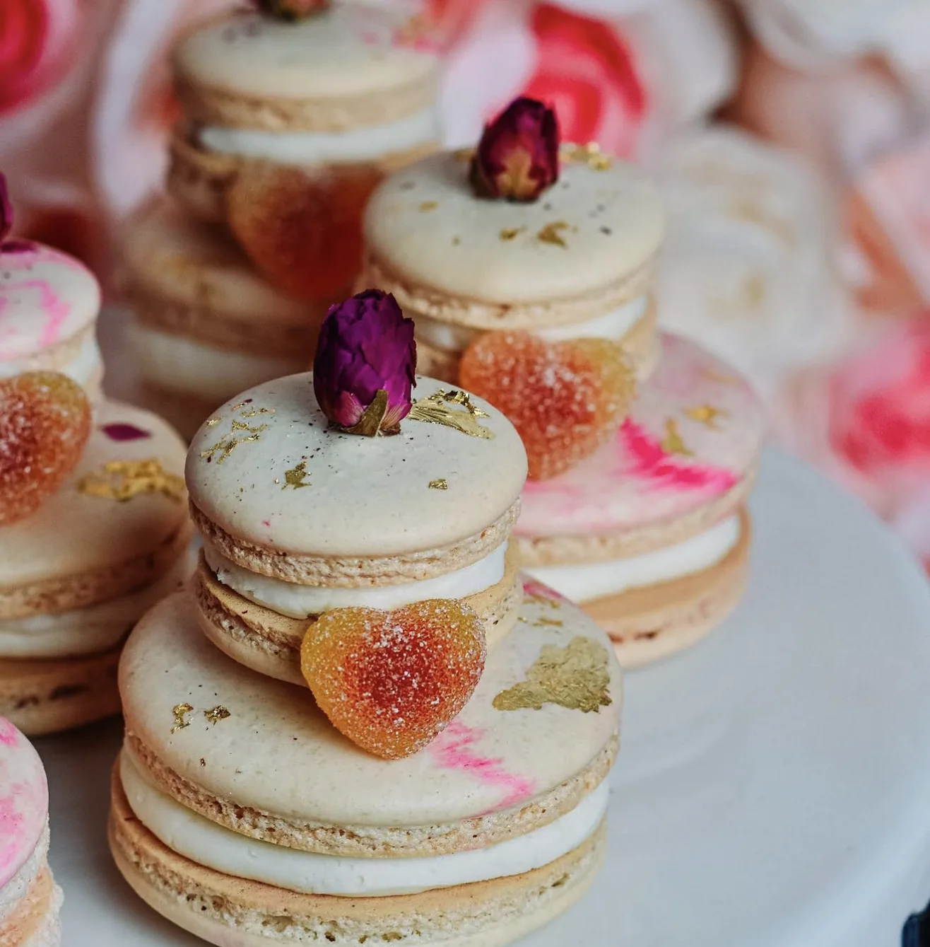 Side view cream macaron tower with gold leaf gummy heart candy and rose bud decor