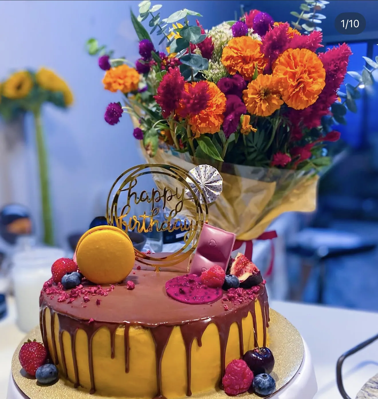 Yellow pink cake with chocolate drip raspberries disc mango macaron and chocolate bar shard