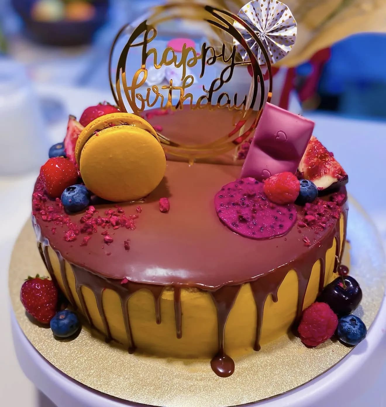 Royal blue glaze cake with macaron meringue kiss fresh blueberries and gold flecks on cream base