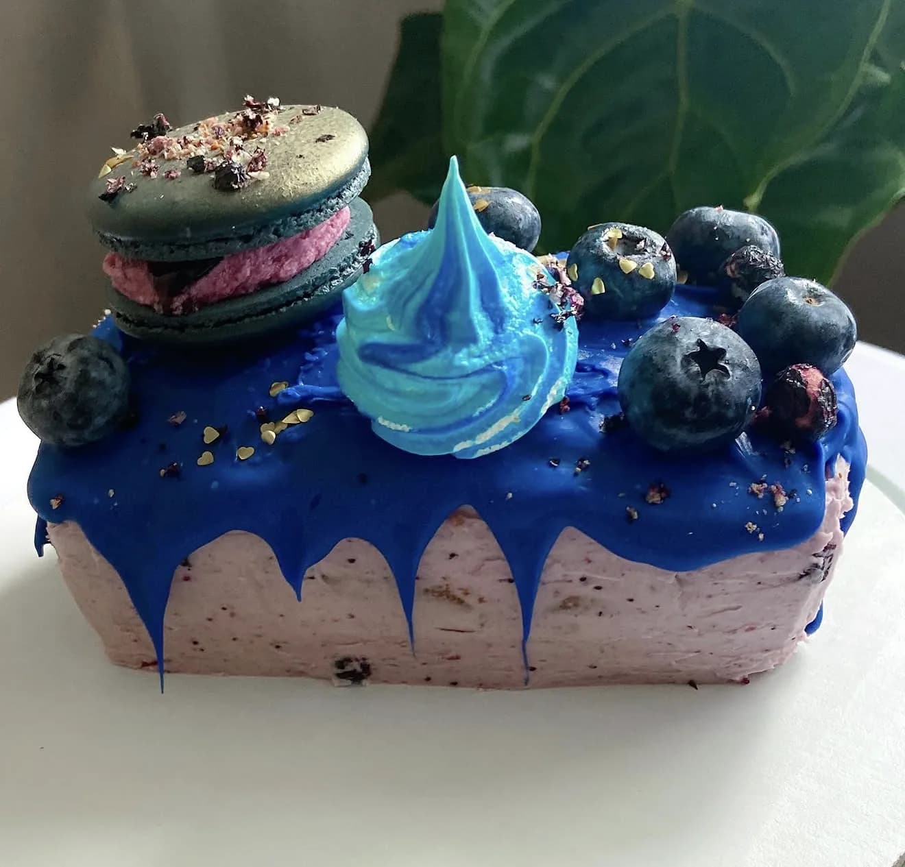 Round royal blue drip cake with blueberries meringue swirl macaron topper and almond crumble